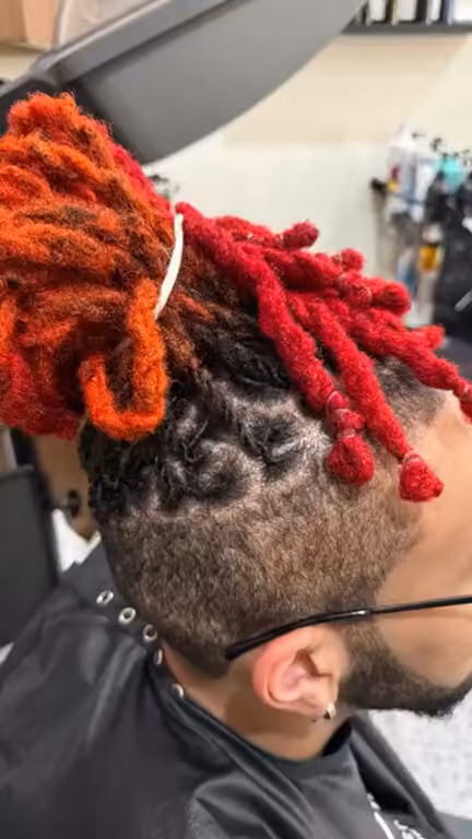 Fire-red locs with a skin fade, side view