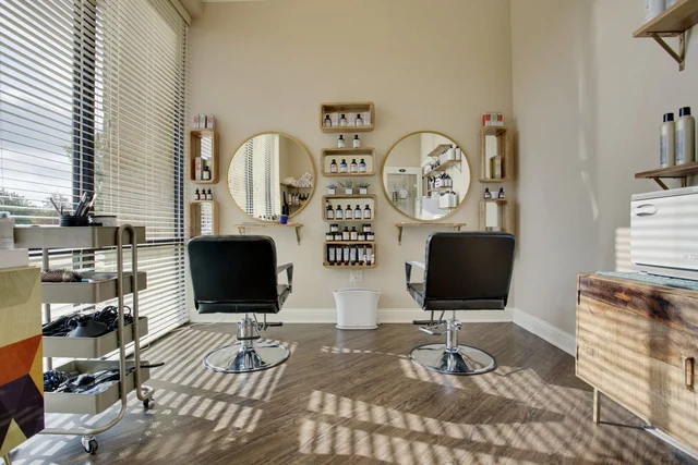 Two styling chairs, mirrors and white cabinetry in an individual suite.