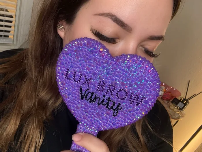 Finished brows in Lux Brow Vanity’s portfolio, above a purple branded mirror.